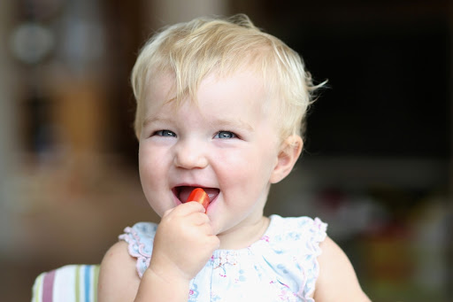 Very happy cute baby girl biting on delicious fresh tomato &#8211; pt