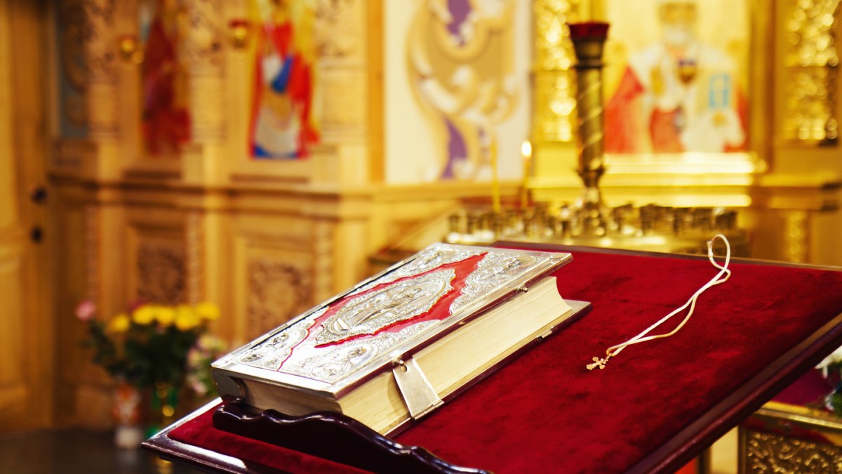 Holy Bible and Orthodox cross prepared for christening ceremony in russian church