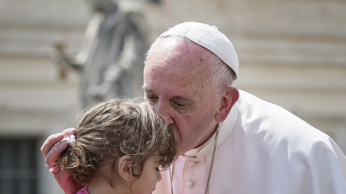 Pope Francis kisses and blessing a little girl