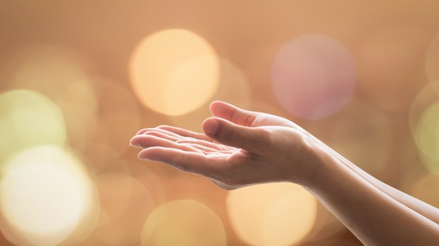 Empty open hands with palms up and candle lights bokeh in warm gold color tone: Isolated female empty open hands praying in warm tone background: Peace of mind, mental health concept: Humanity aid