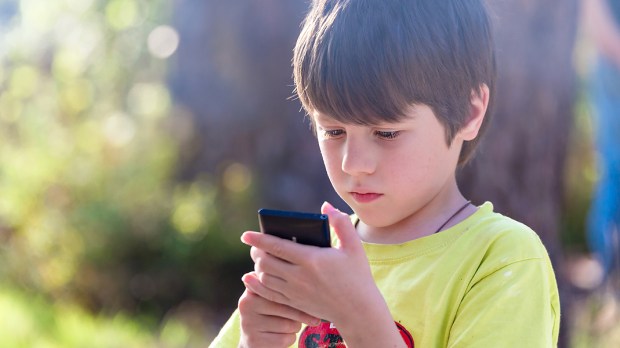 WEB3 LITTLE BOY OUTSIDE SMARTPHONE PHONE TEXTING GAMES Shutterstock