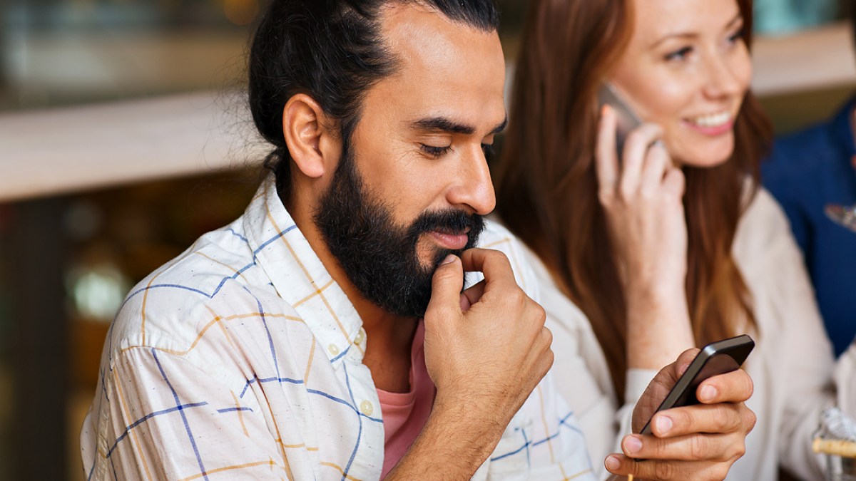 WEB3 MAN ON PHONE WITH FRIENDS AT RESTAURANT Shutterstock