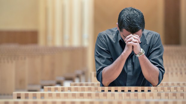 WEB3 YOUNG MAN PRAYING CHURCH BLUE SHIRT Shutterstock
