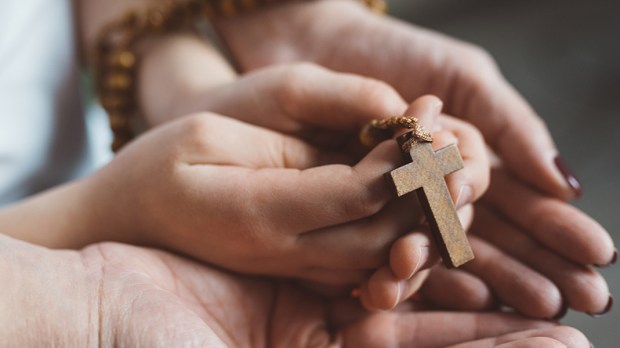 MÃOS DE ADULTO E CRIANÇA SEGUNRADO TERÇO