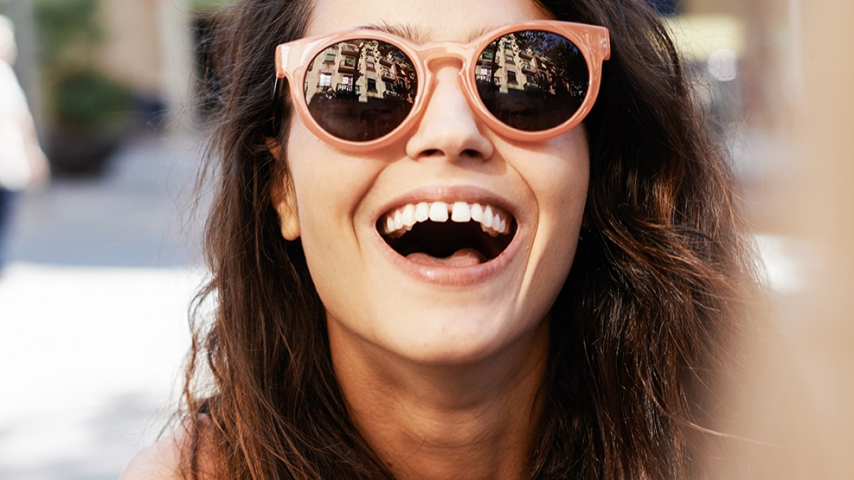 WEB3-SUNGLASSES-SMILE-LAUGHING-SUMMER-FUN-WOMAN-Stocksy-United