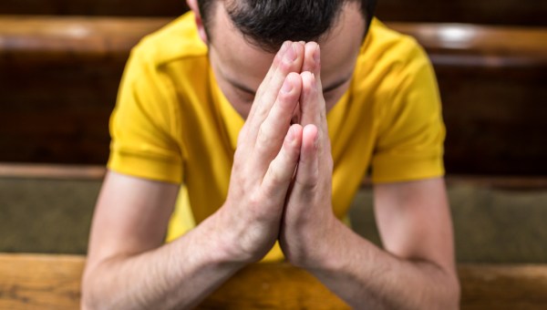 MAN PRAYING IN CHURCH PEW