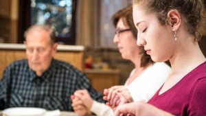 FAMILY PRAYING AT DINNER