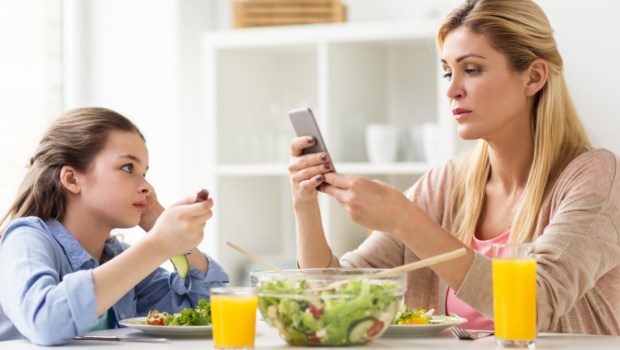 Mãe e filha na mesa com seus telefones