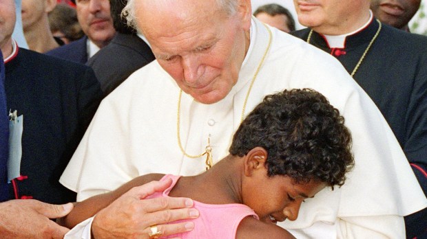 Uma criança abraça o Papa João Paulo
