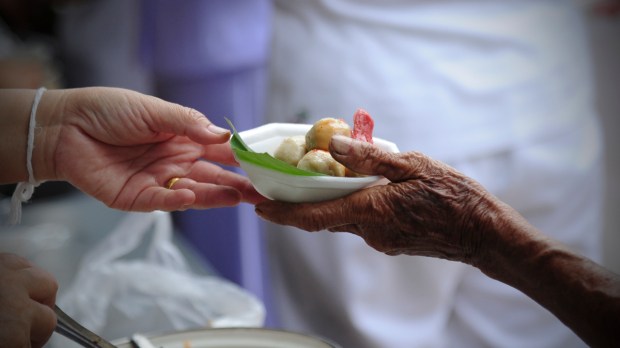 Mão entregando prato de comida a outra pessoa pobre