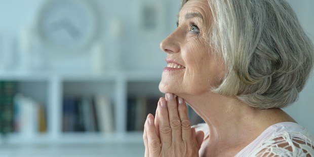 ELDERLY WOMAN PRAYS,