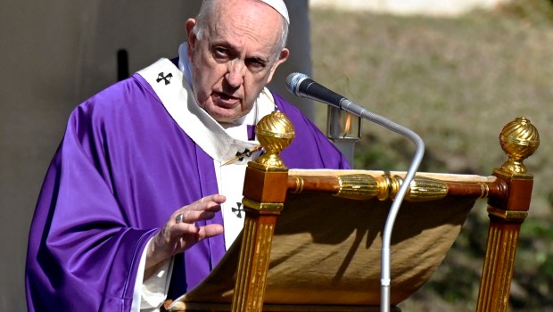 Pope Francis stands by graves with flowers at the French military cemetery