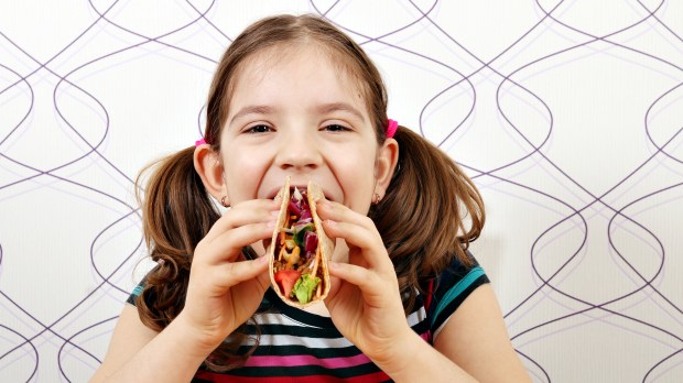 Criança comendo alimento que contém carne