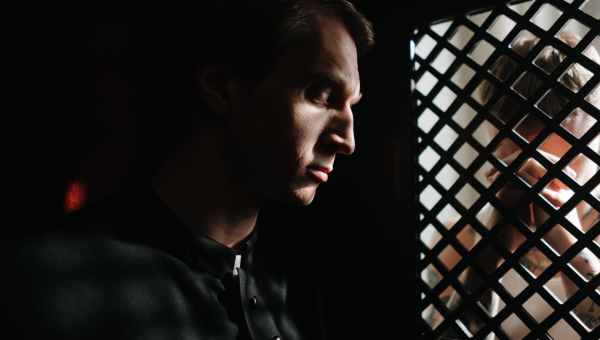 a priest listening to the person confessing