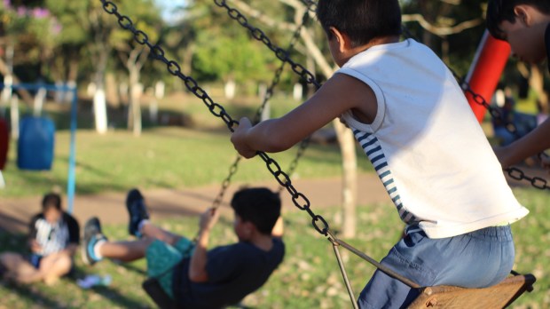 children playing in the park playground on a sunny and green day