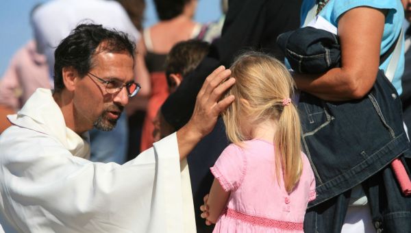 ksiądz błogosławi dziewczynkę