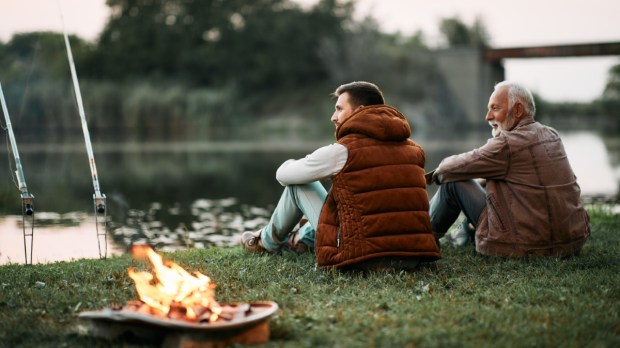 pessoas sentadas ao ar livre junto ao fogo e a um lago
