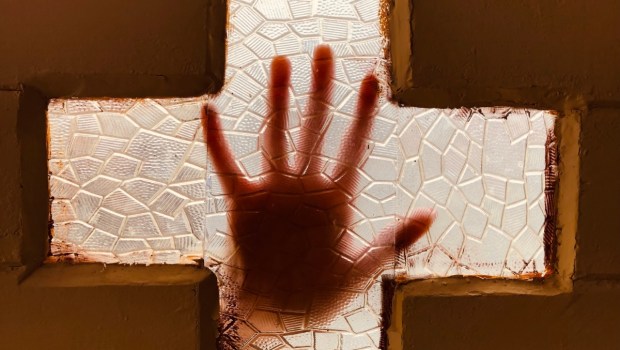 mão sobre cruz em sinal de desespero