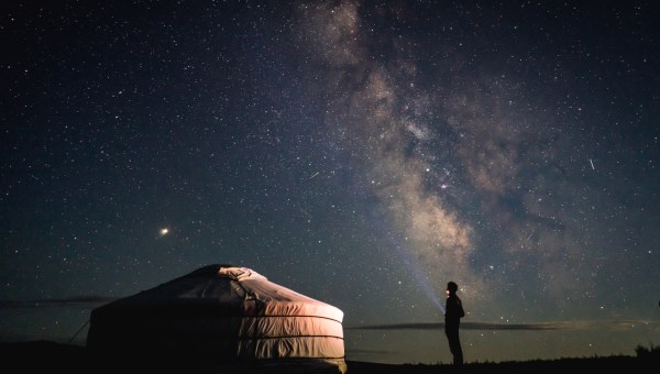 Pessoa olhando o céu estrelado representa busca por Deus