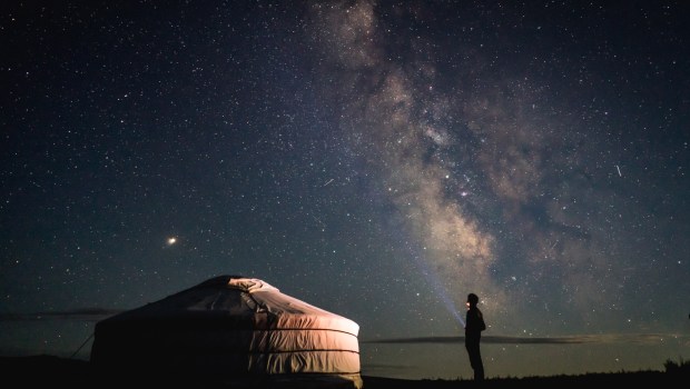 Pessoa olhando o céu estrelado representa busca por Deus