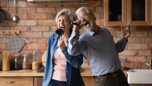 Casal de idosos se divertindo e cantando com utensílios de cozinha