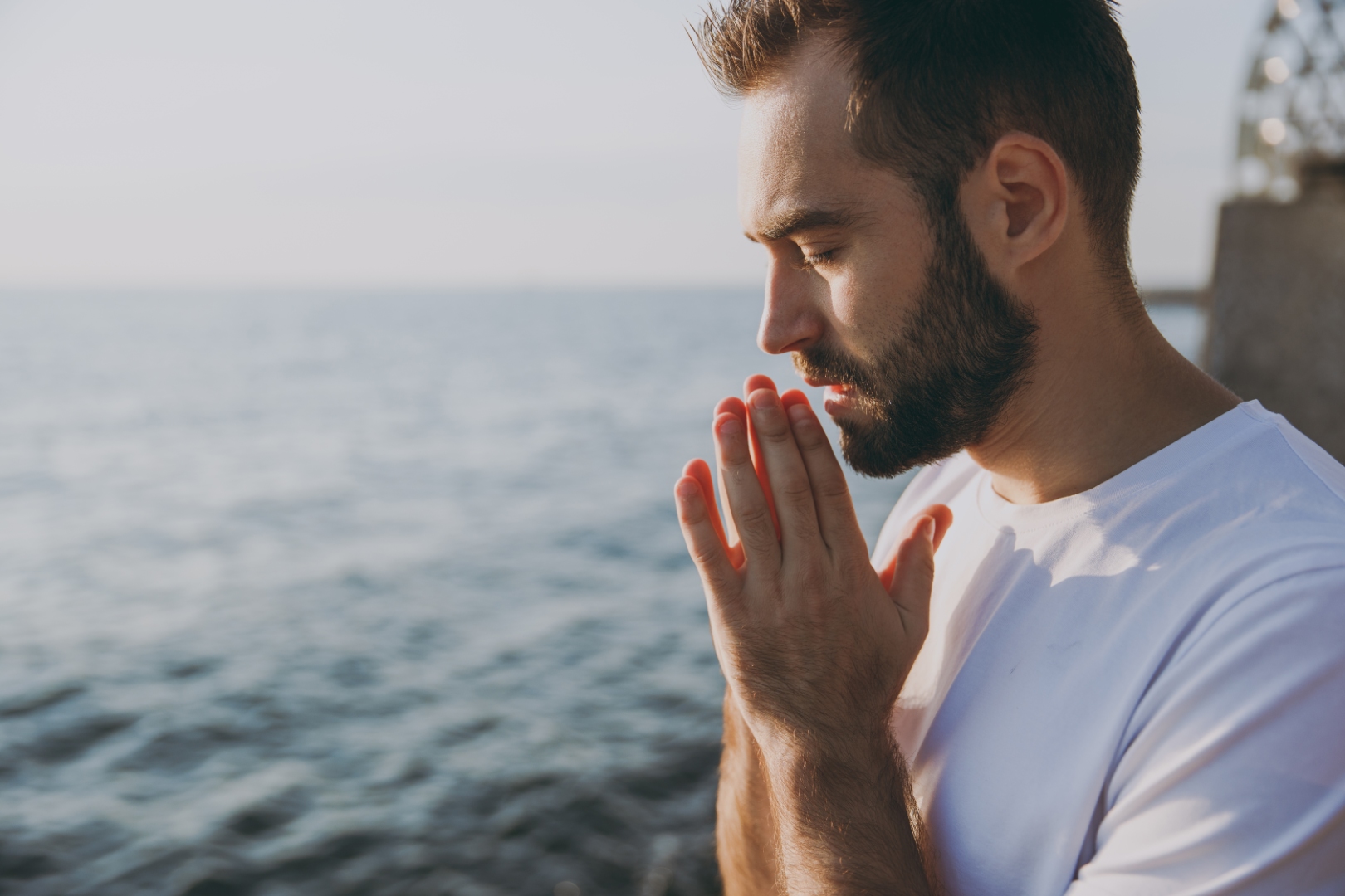 mężczyzna modli się nad jeziorem o poranku