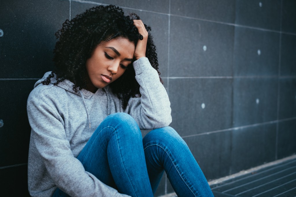 depressed teen girl sitting against wall