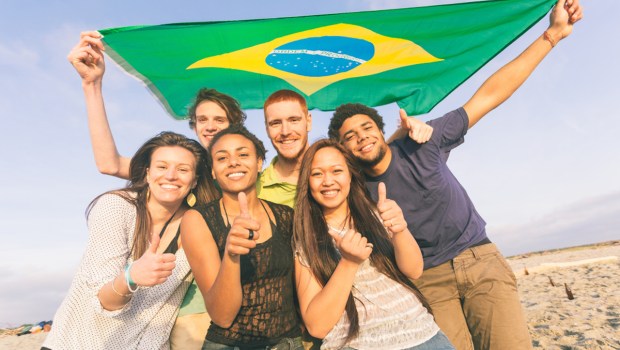 Jovens brasileiros com bandeira na praia