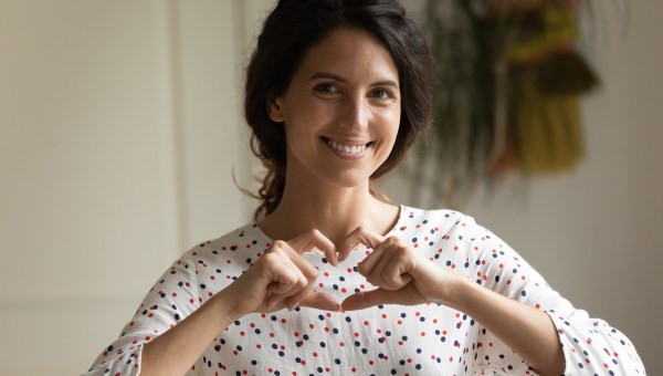 Mulher faz coração com as mãos em sinal de amor e gratidão