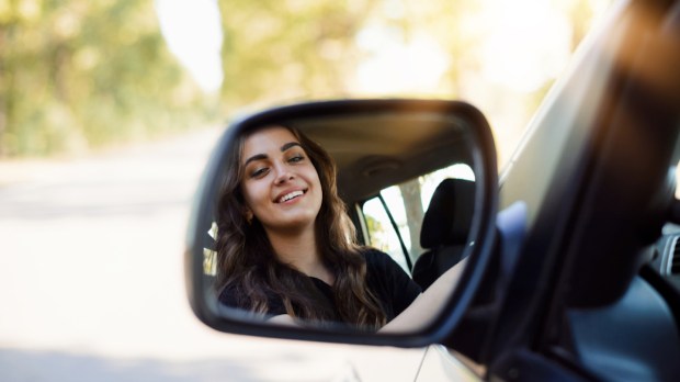 Mulher olhando no retrovisor do carro