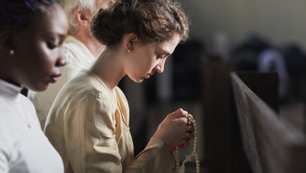 Jovens rezando o terço em igreja