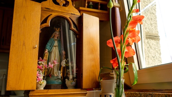 imagen de una virgen colocada en un altar de madera con una tapa para llevar de una casa a otra