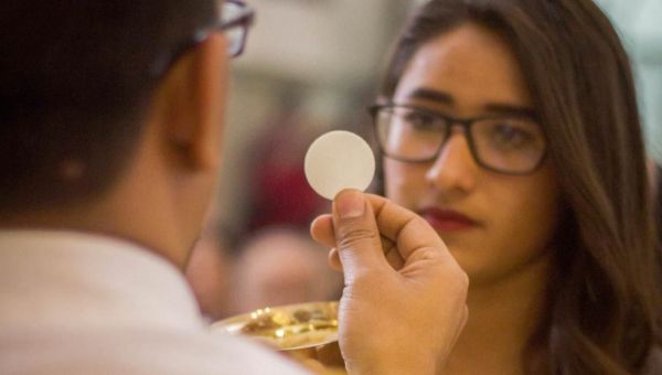 Padré dá a comunhão a uma mulher