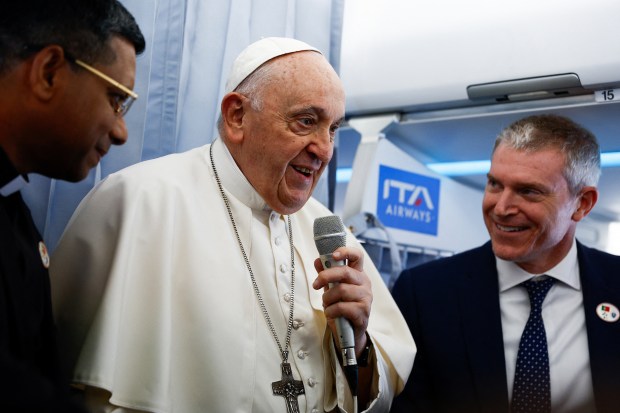 Pope Francis talks to journalists aboard his plane before landing at the Figo Maduro air base in Lisbon to attend the World Youth Day