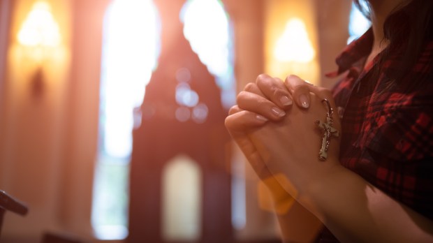 Woman praying with rosary in hands