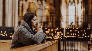 Woman praying in church with candels