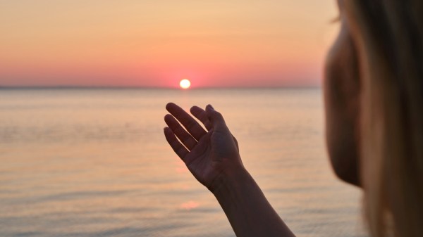Girl looks at the sunrise by the sea
