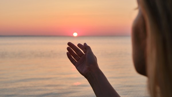 Girl looks at the sunrise by the sea