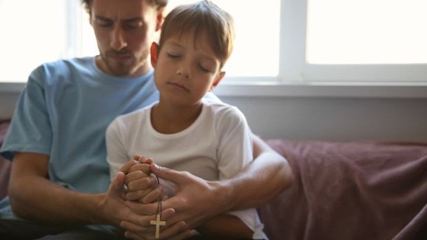 Pai e filho rezando o terço