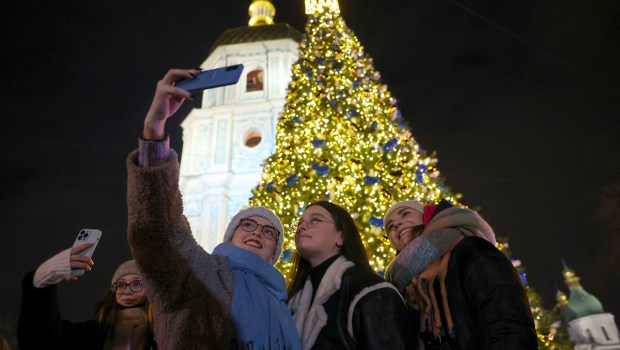 People taking selfie in front of Kyiv Ukraine Christmas tree