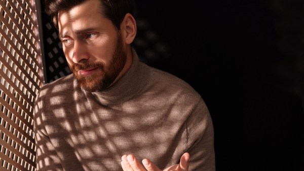 Man talking to priest during confession in booth, space for text