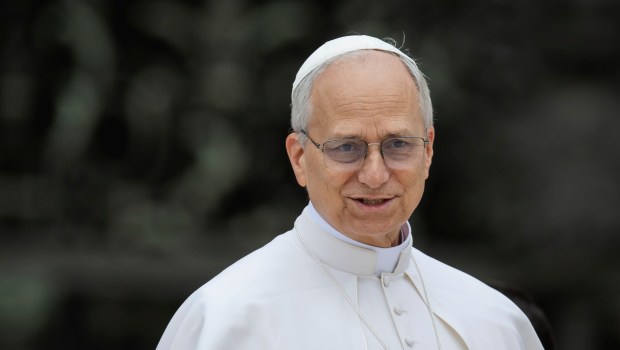 A woman kisses the hand Pope Leo XIV at the end of his first weekly general audience at St Peter's Square in The Vatican on May 21, 2025